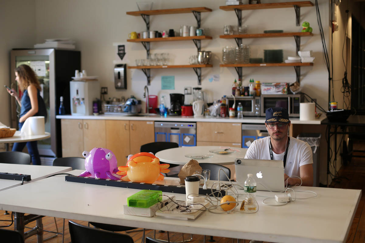 a person on his laptop with the ITP kitchen in the background